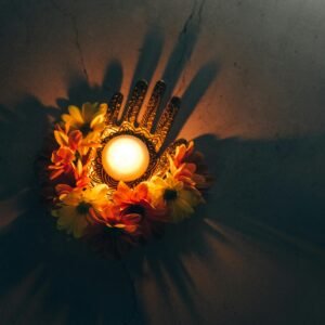 Home A warm Diwali decoration with a lit candle surrounded by vibrant flowers, casting shadows.