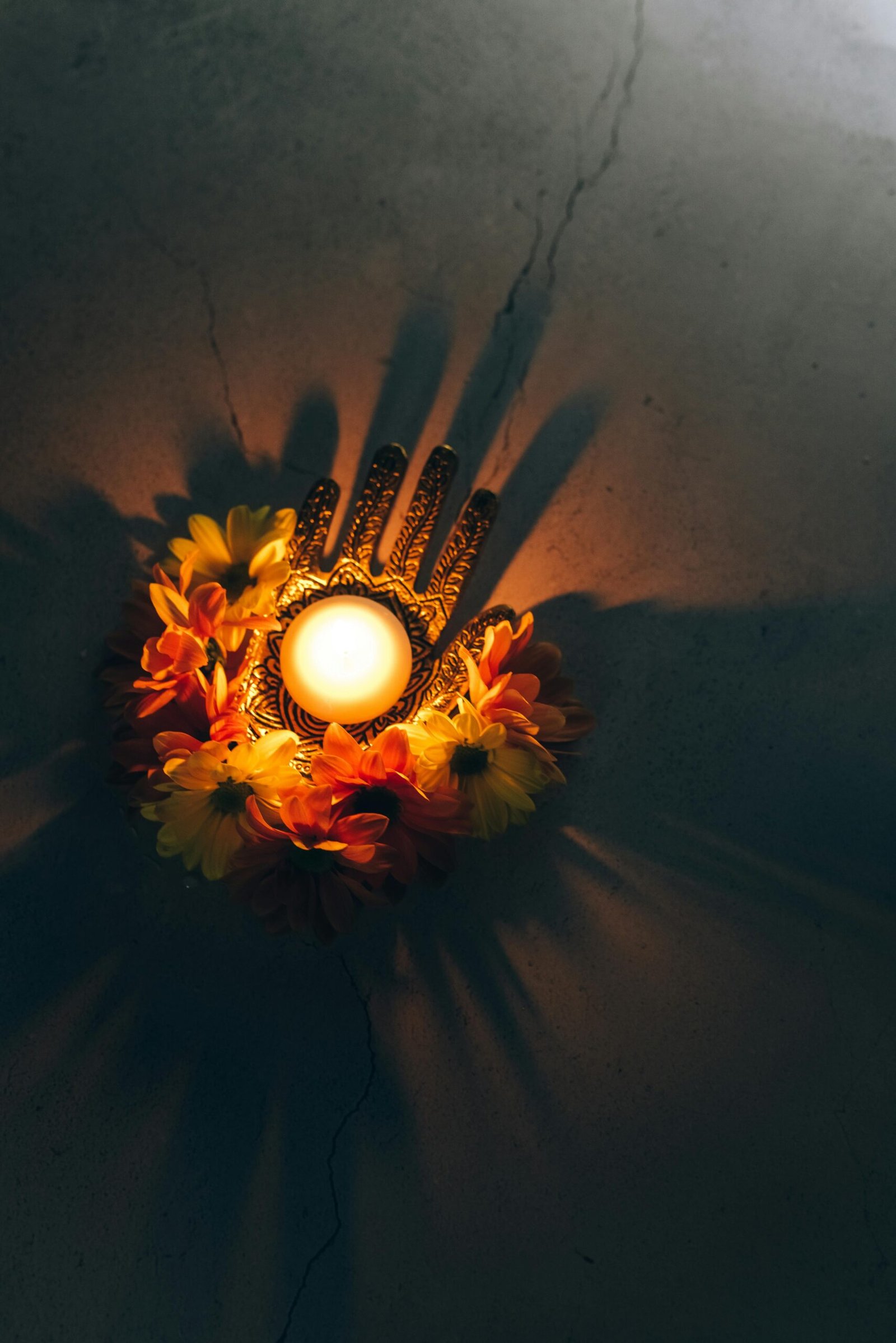 pexels photo 7121488 7121488 A warm Diwali decoration with a lit candle surrounded by vibrant flowers, casting shadows.